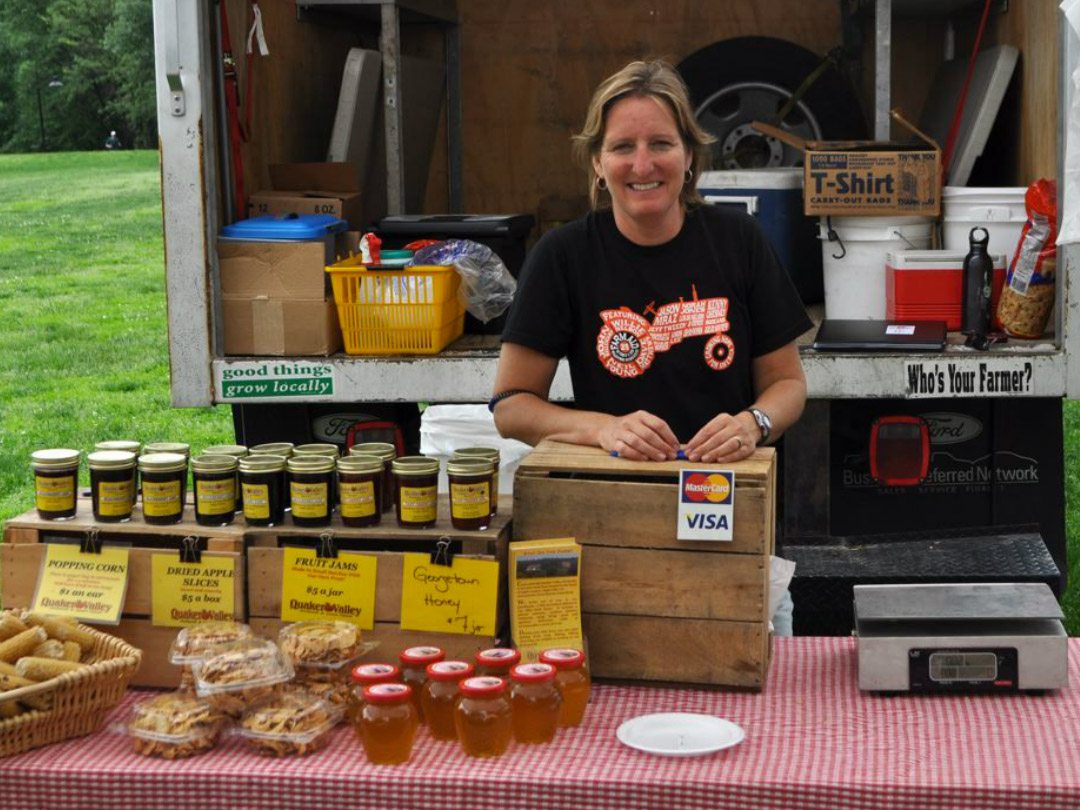 Rose Park Farmers Market - Woman selling local honey and baked goods behind a table
