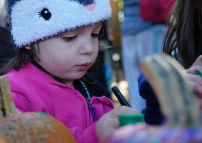 Friends of Rose Park - Halloween 2018 - child in hat painting a pumpkin