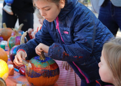 Friends of Rose Park - Halloween 2018 - child in coat painting a pumpkin with glitter pen