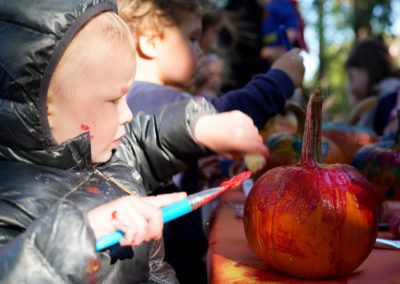 Friends of Rose Park - Halloween 2018 - child painting pumpkin with paint on hands and face
