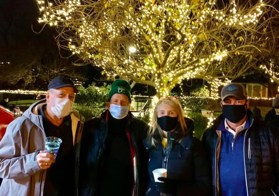 Friends of Rose Park - Winter Market 2020 - Friends standing outside with warm drinks, in masks, in front of a lit tree